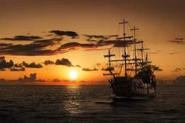 an old ship sailing at sunset
